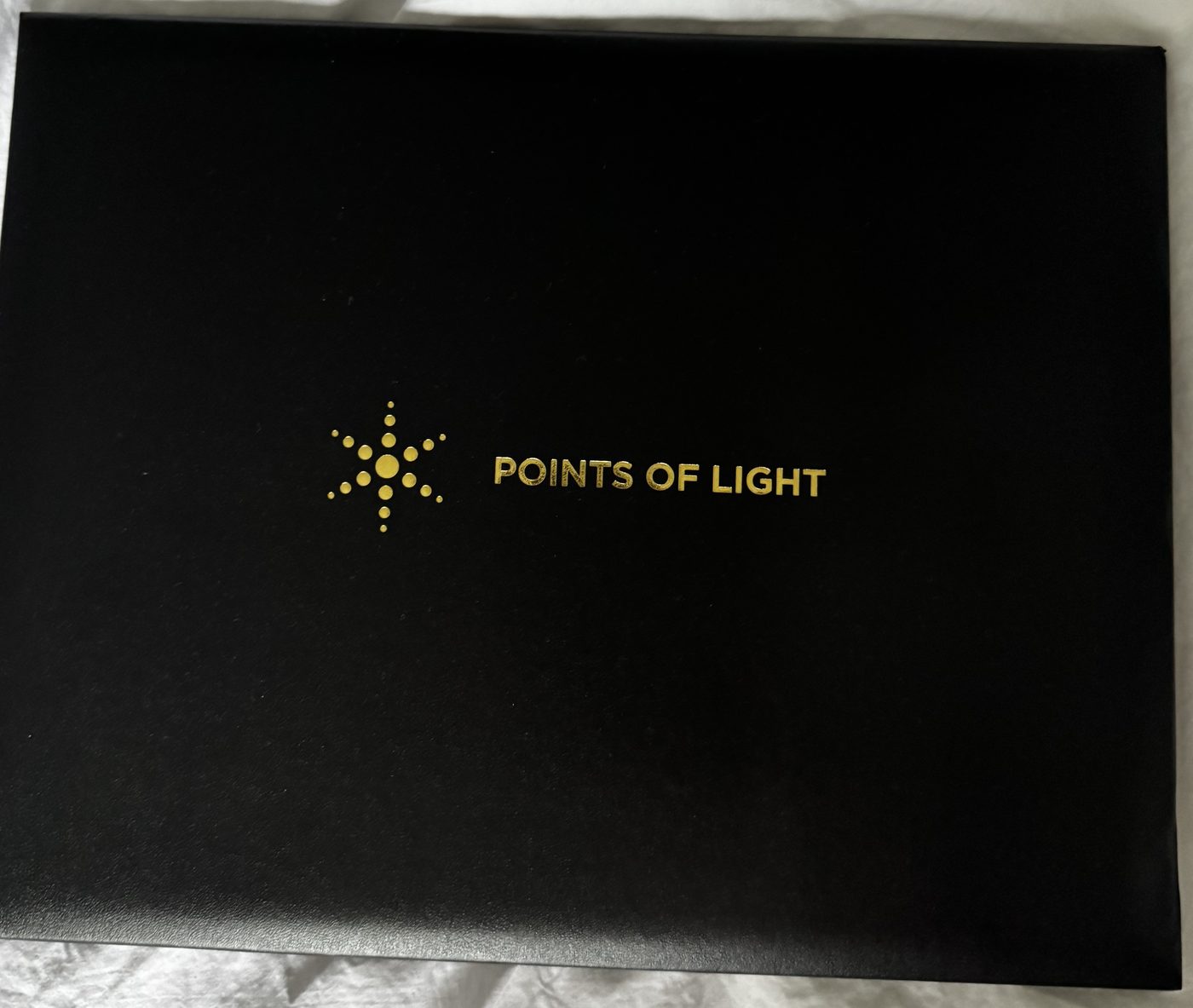 The Points of Light award presentation folder, embossed in gold with the Points of Light star emblem